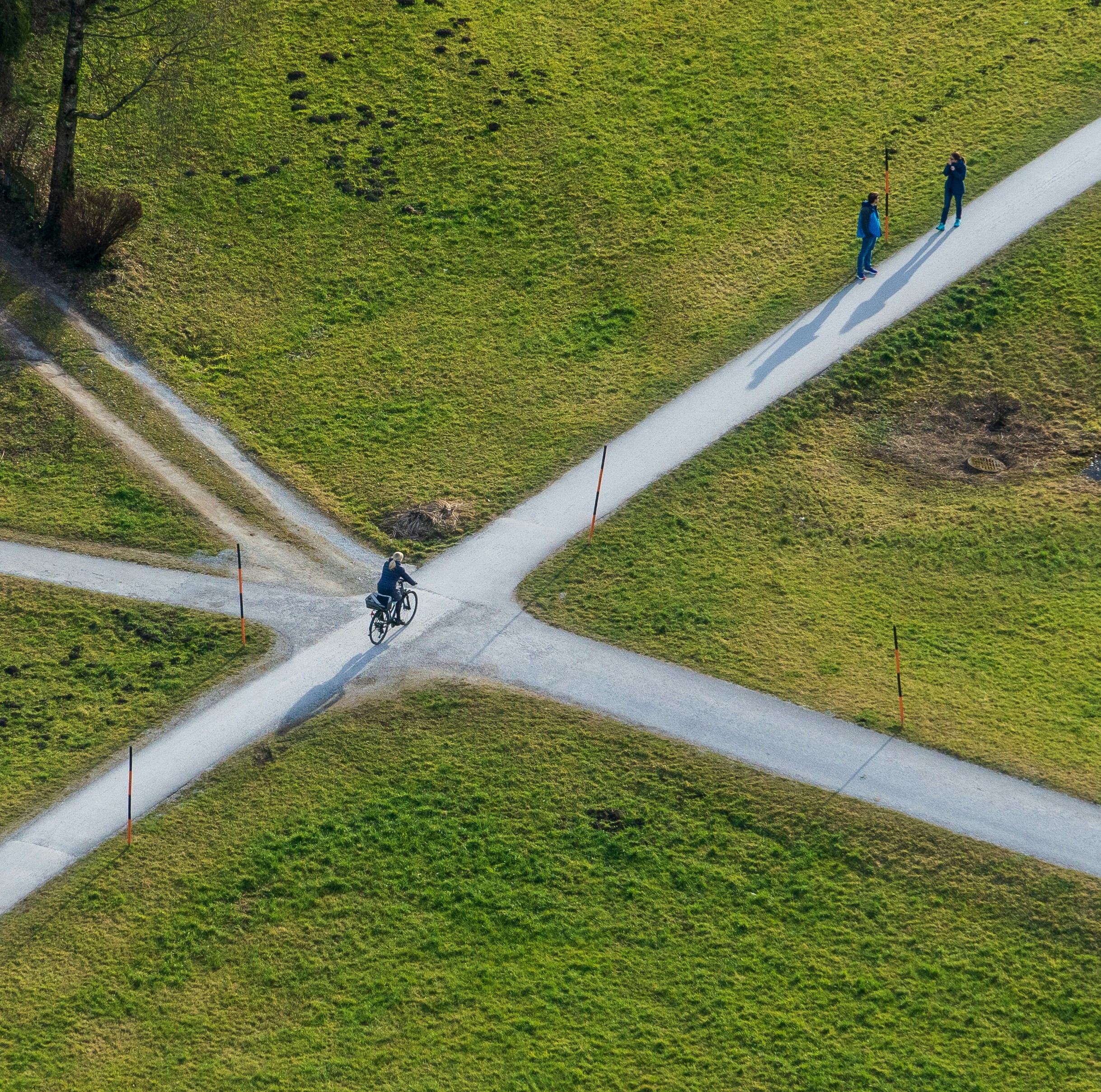 Aerial view of a cyclist and two pedestrians on an X-shaped path junction