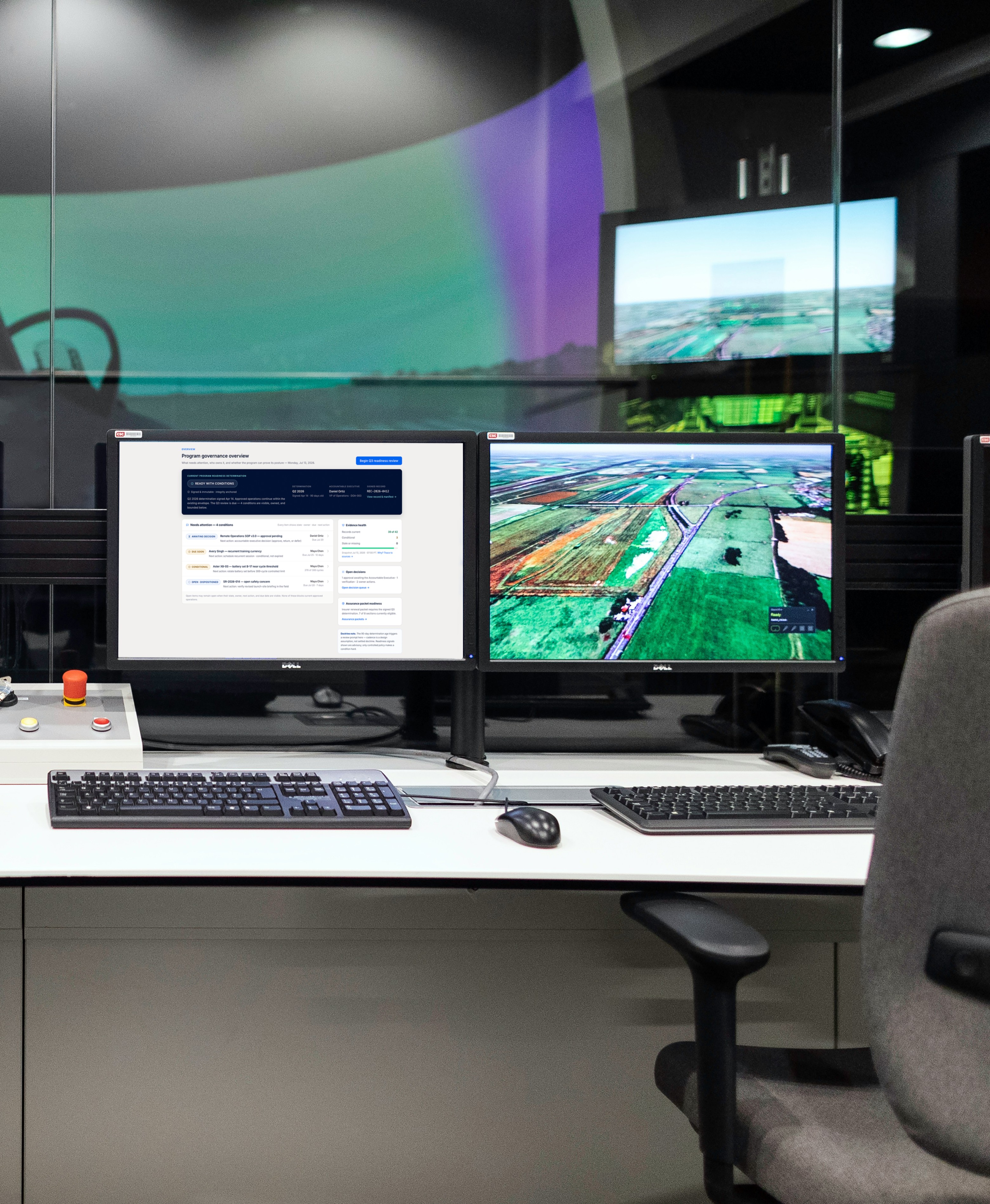 Control room desk with dual monitors showing simulation software and aerial map view