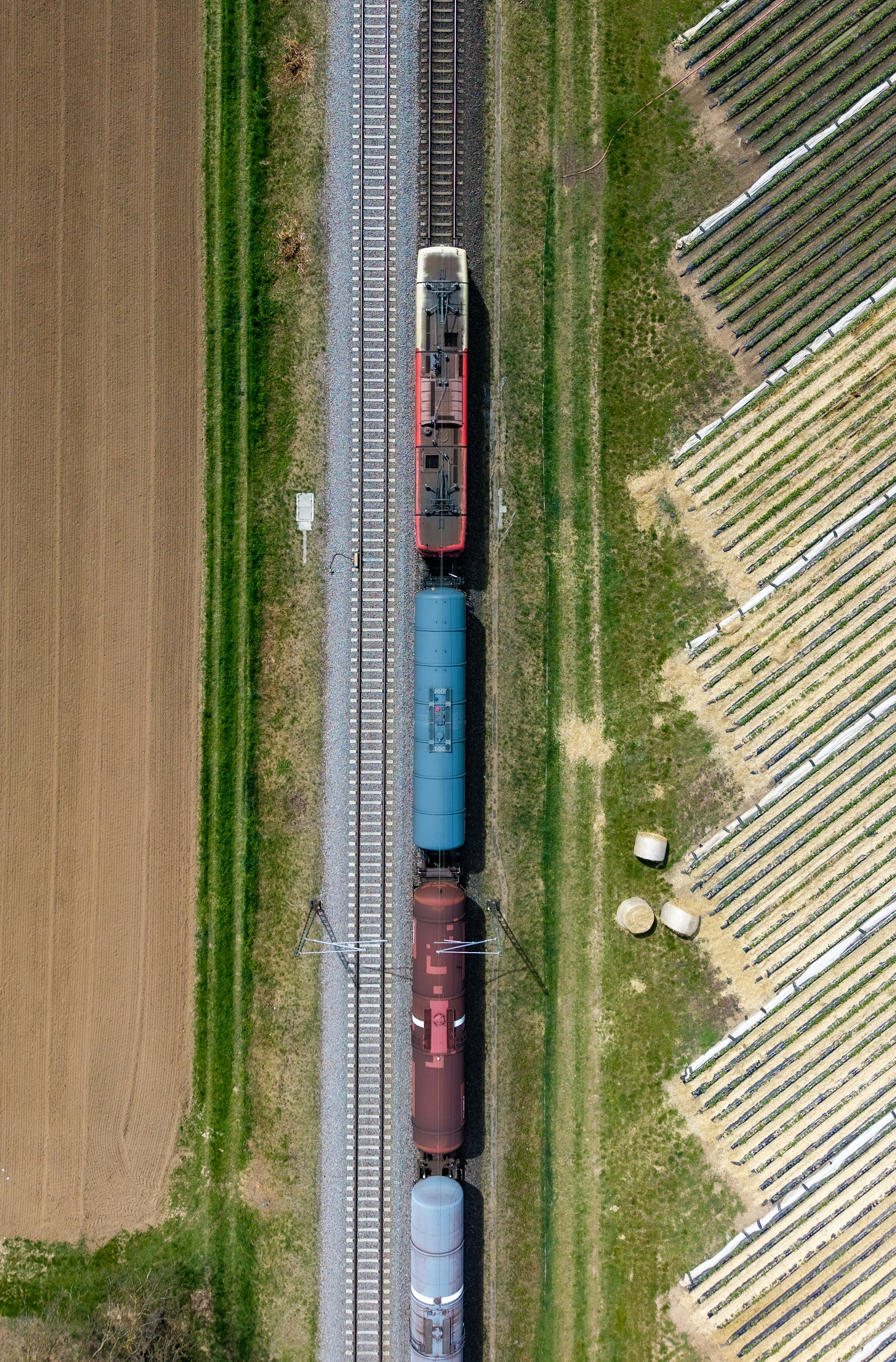 Aerial view of a freight train with tanker cars beside farmland
