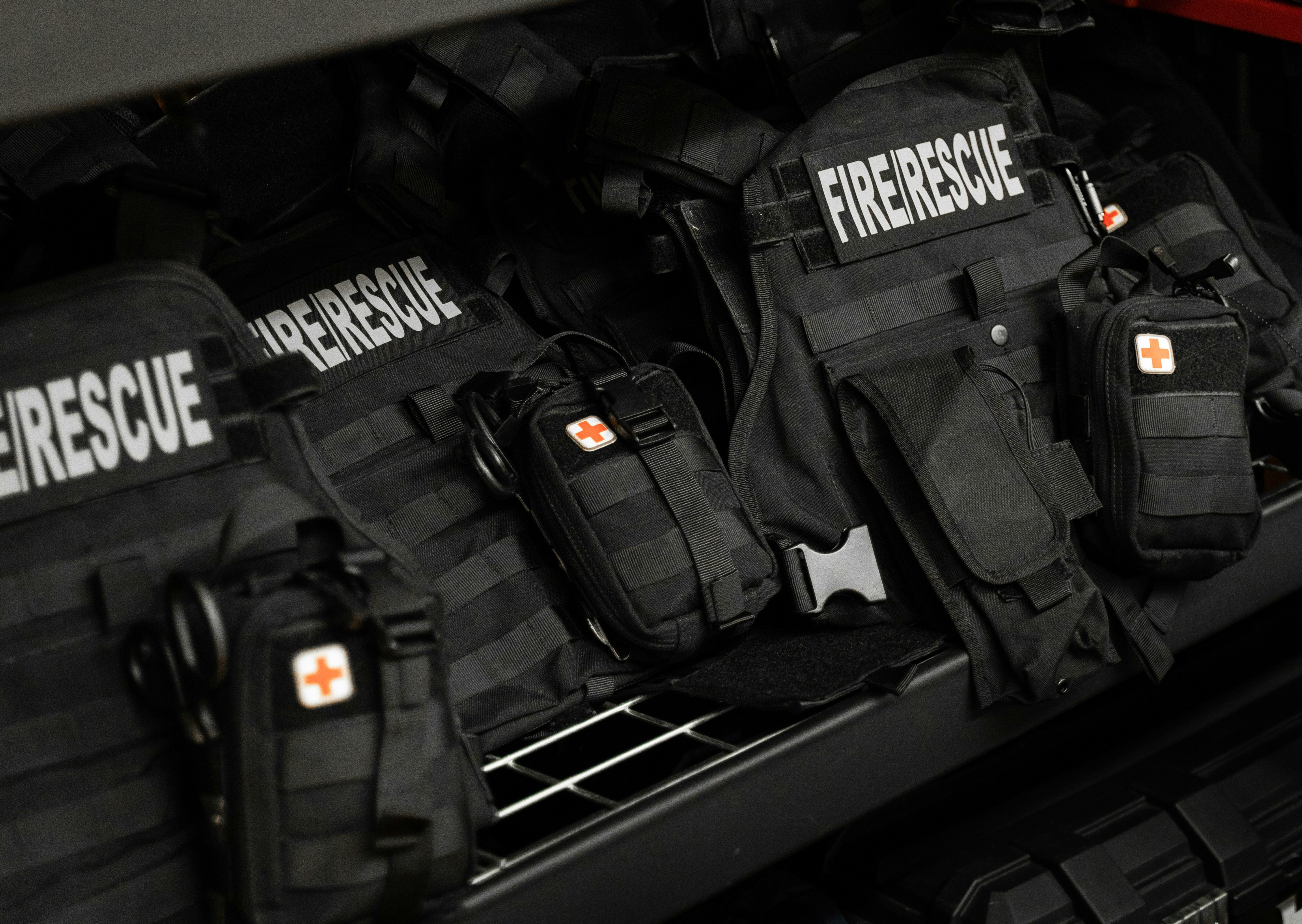 Close-up of black Fire/Rescue tactical vests with first-aid pouches in a truck
